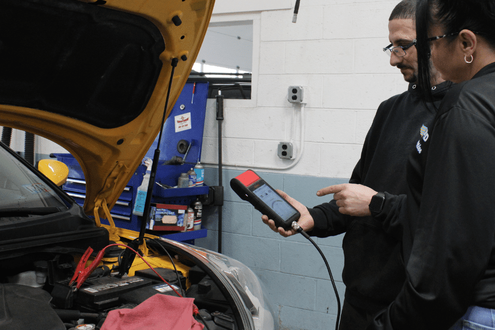 Car battery service, auto repair in Allentown, PA by Allied Automotive. Image of a technician using a diagnostic scan tool while reviewing results with a customer. Highlighting Allied Automotive’s commitment to accurate troubleshooting and reliable vehicle performance.
