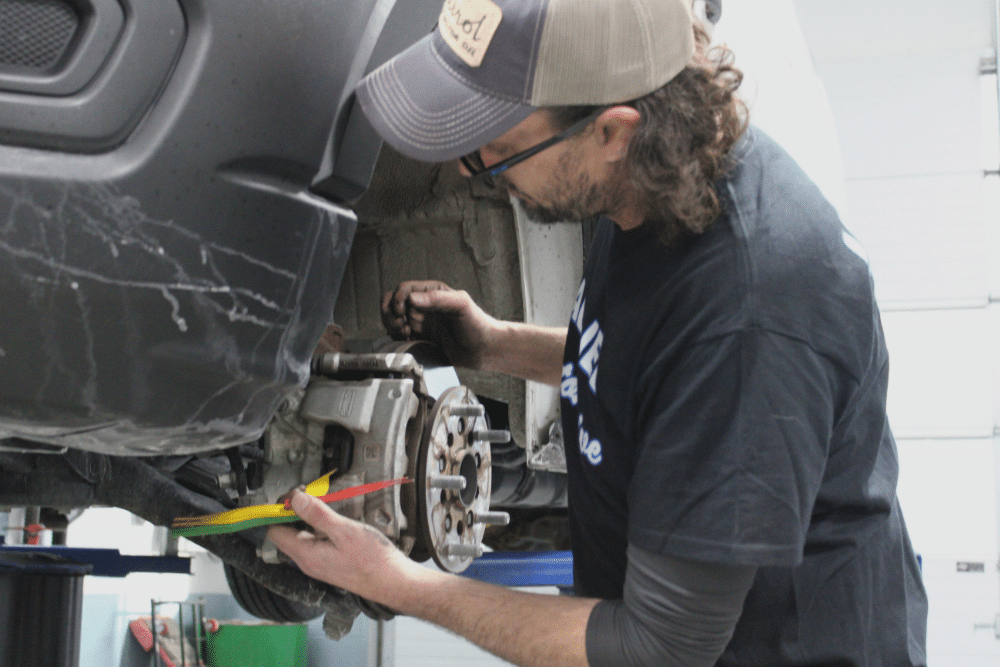 Comprehensive Road Trip Brake Repair and A/C Service in Allentown, PA At Allied Automotive. A mechanic inspecting a car's disc brake assembly and using a thickness gauge to measure the brake pad wear during a brake service.