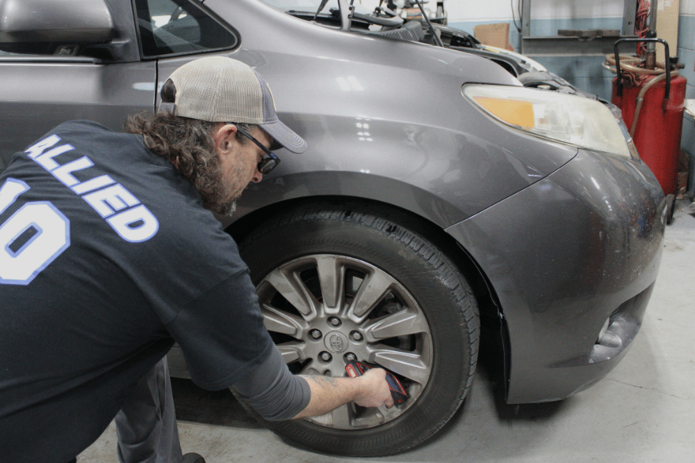 Honda or Toyota Service in Allentown, PA At Allied Automotive. Mechanic servicing the front wheel of a grey Toyota