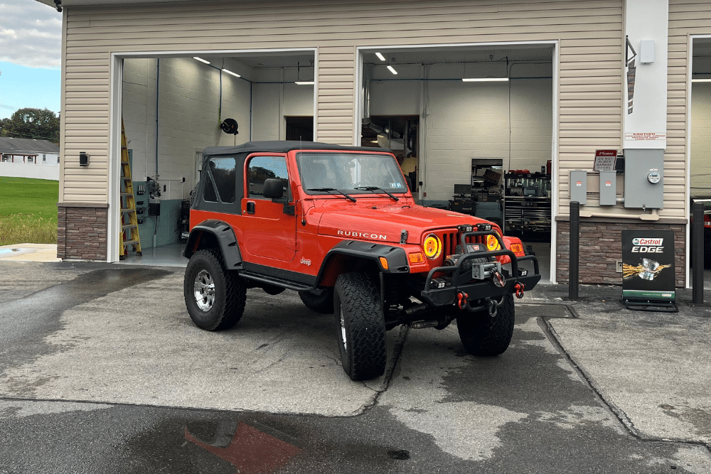 Jeep Death Wobble & Pentastar Engine Repair, Jeep Auto Repair in Allentown PA At Allied Automotive. Orange Jeep Wrangler Rubicon parked outside a shop.
