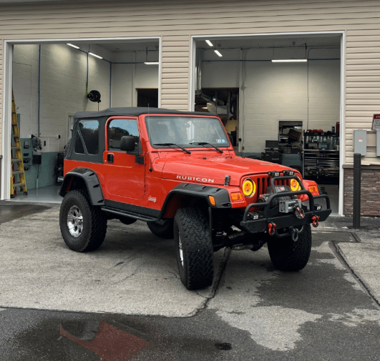Jeep Death Wobble & Pentastar Engine Repair, Jeep Auto Repair in Allentown PA At Allied Automotive. Orange Jeep Wrangler Rubicon parked outside a shop.